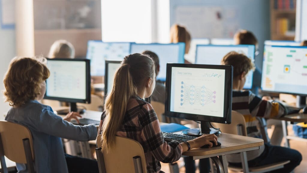 Children in a classroom using desktop devices to learn